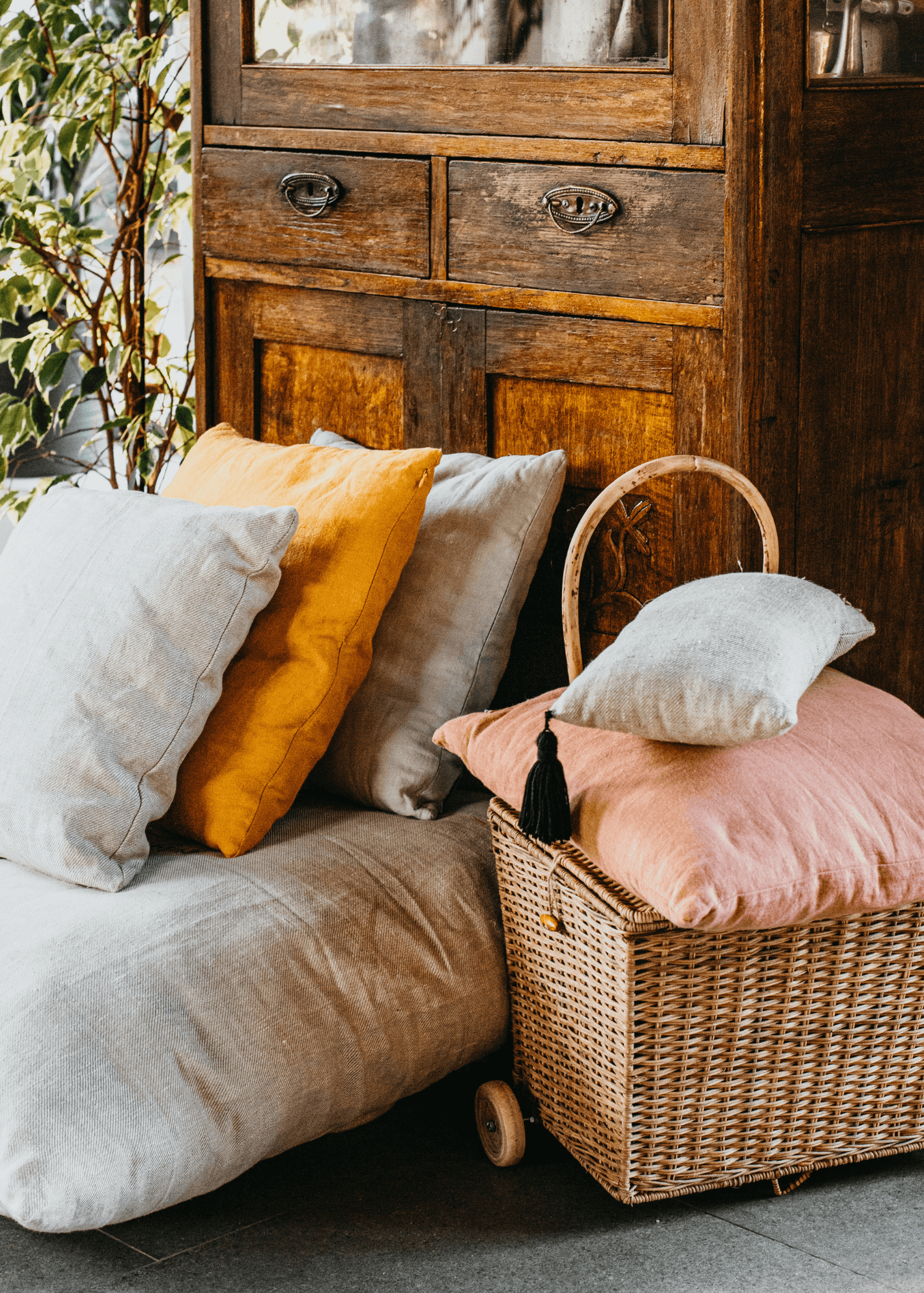 Coussin en lin beige sur une chauffeuse devant une armoire en bois