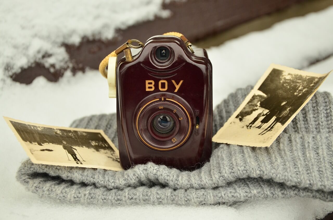 Ancienne camera déposé sur un tissus en laine et entouré de photo en noir et blanc